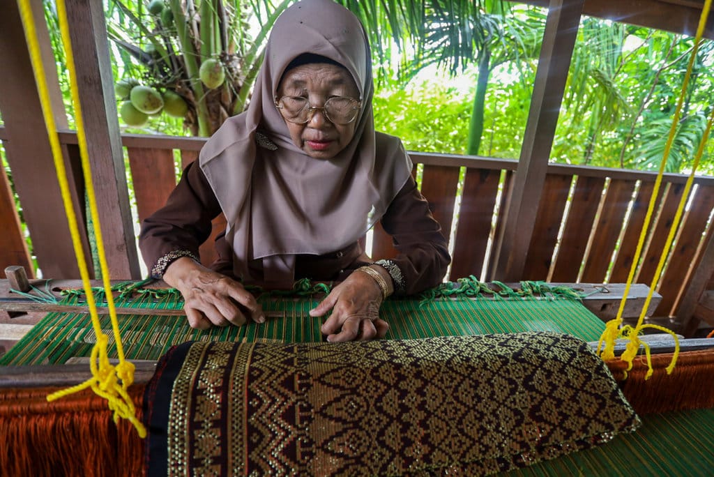 Darliana menenun kain songket dengan alat tradisional di rumah produksi Mutiara Songket. Foto : tirto.di/Firhan Farabi Kain Tenun Tradisional Aceh