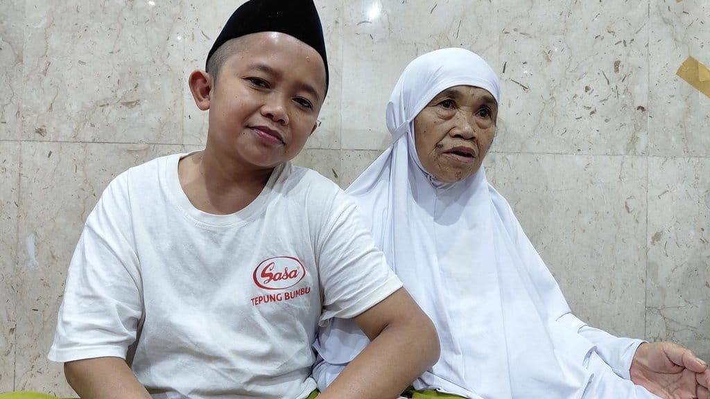 Mbah Painah (65), jemaah haji asal Wonosobo, Jawa Tengah, ditemani anak bungsunya, Sabar (35), saat ditemui Tim Media Center Haji di Sektor 8 Kawasan Misfalah, Makkah, Minggu (7/6/2026). Abdul Aziz/Tirto/MCH 2026. Mbah Painah