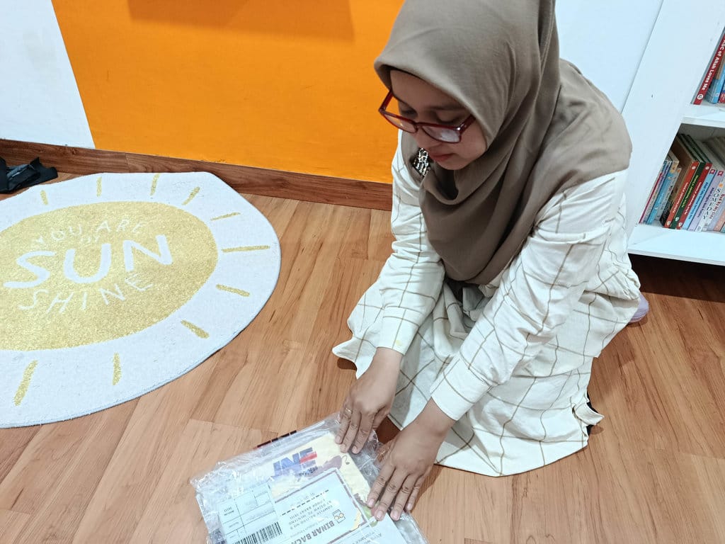 Pendiri Perpustakaan Binar Baca, Jihan, sedang membuka paket kiriman pengembalian buku dari pelanggannya melalui ekspedisi JNE. tirto.id/bayu Septianto Perpustakaan Binar Baca