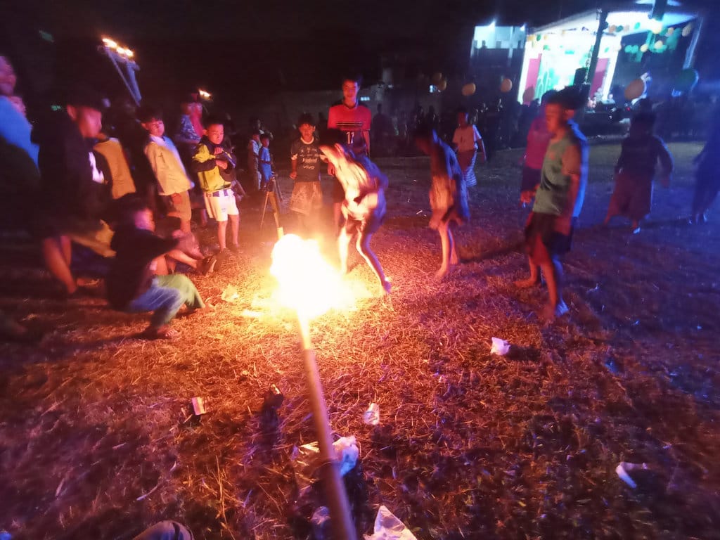 Anak-anak bermain sepakbola api dan bambu gila dalam kegiatan menyambut Tahun Baru Islam 1 Muharram 1448 Hijriah di Desa Cibiru Hilir, Kabupaten Bandung, Senin (16/6/2026). tirto.id/Muhamad Nizar. Sepakbola Api dan Bambu Gila di Cibiru Hilir