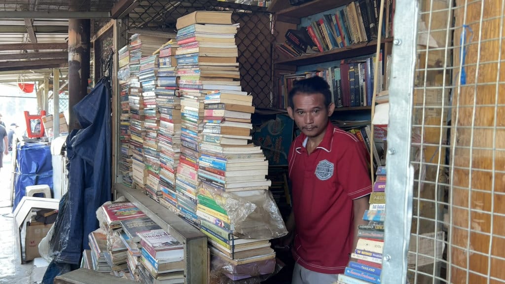 Juntak, salah satu pedagang buku bekas di kawasan samping Terminal Senen, saat ditemui Tirto di lapaknya, Rabu (8/7/2026). tirto.id/Hanang Septioyudho Newsplus Masa Depan Lapak Buku Bekas Senen
