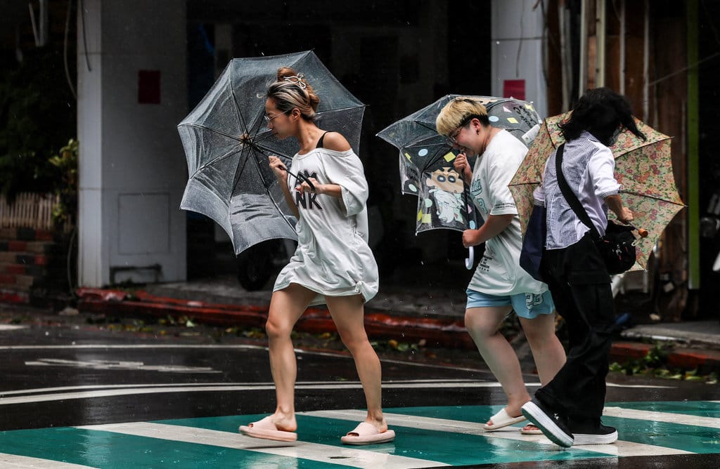 Pejalan kaki yang memegang payung melintasi jalan di tengah angin kencang dan hujan saat Topan Bavi melintas di lepas pantai timur laut Taiwan, tepatnya di Keelung, pada 11 Juli 2026. Lebih dari 14.000 orang di Taiwan telah meninggalkan rumah mereka dan banyak toko tetap tutup, sementara topan yang sebelumnya menghantam pulau-pulau terpencil di barat daya Jepang itu bergerak menuju Tiongkok pada 11 Juli. AFP/ I-Hwa Chen Topan Bavi China