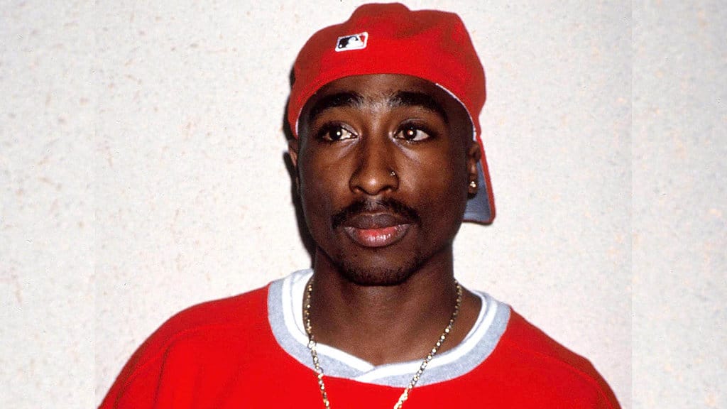 1994 - New York, New York, AS - Tupac Shakur mengenakan perhiasan emas dan sweter merah—warna khas geng 'Bloods' asal Georgia. (Credit Image: © John Barrett/ZUMA Wire) Tupac Shakur
