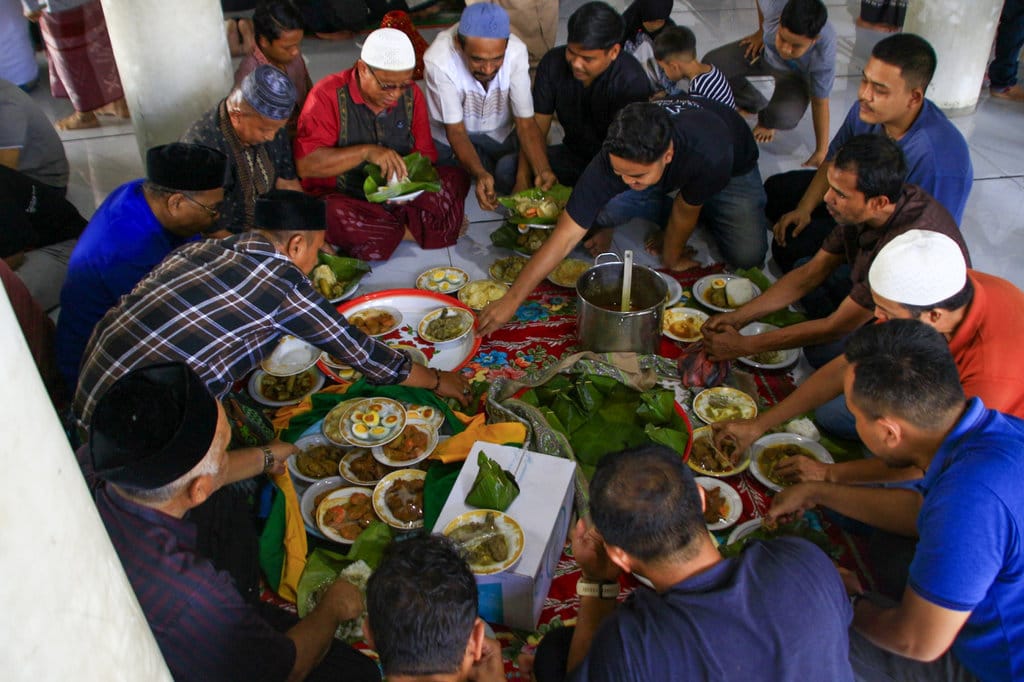 Masyarakat menikmati hidangan maulid Nabi Muhammad di Meunasah (surau) di kabupaten Aceh Besar. (Foto : tirto.id/Firhan Farabi) Newsplus Merawat Tradisi dari Sebungkus Nasi