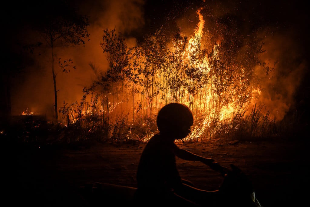 Warga mengendarai sepeda motor saat melintas di samping api yang membakar hutan dan lahan di Kecamatan Sebangau, Kota Palangka Raya, Kalimantan Tengah, Rabu (9/9/2026). ANTARA FOTO/Bayu Pratama S/nym. Karhutla dominasi kejadian bencana di Indonesia