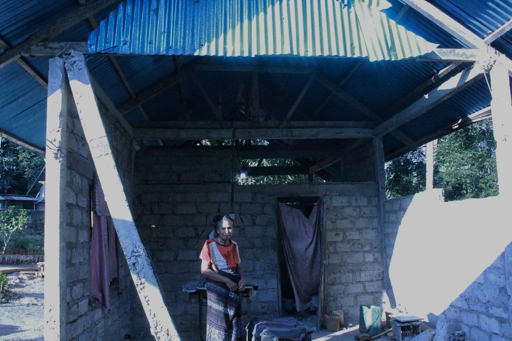 Mama Dominika Wea berdiri di rumahnya yang roboh akibat gempa di Kampung Cawalo, Desa Rokirole, Kecamatan Palue, Kabupaten Sikka, Rabu (16/9/2026) siang. (Foto: Mario Sina) Newsplus 32 Hari Pascagempa Flores