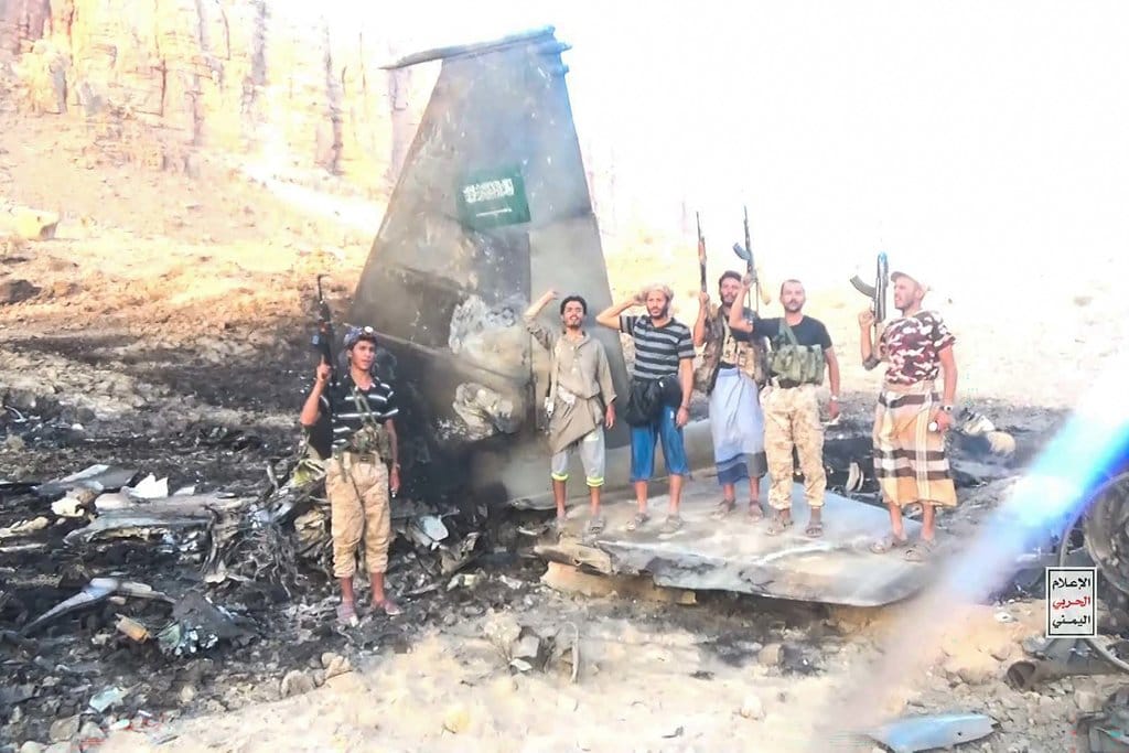 pejuang yang berafiliasi dengan otoritas Houthi di tengah puing-puing—yang menurut militer Houthi merupakan bangkai jet tempur F-15 milik Arab Saudi—yang ditembak jatuh di provinsi Marib, wilayah tengah Yaman. foto/AFP Bangkai Pesawat Arab Saudi