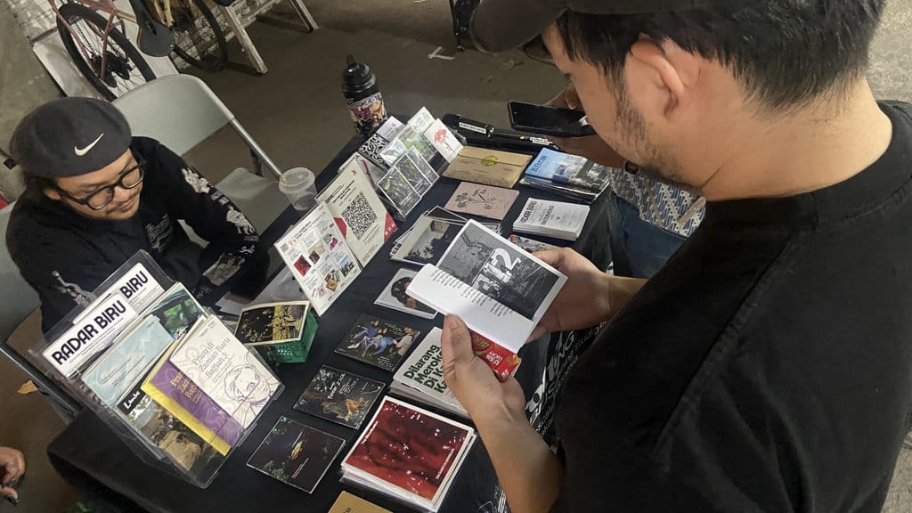Pengunjung melihat koleksi zine terbitan Trotter Tales yang ditampilkan di lapak Raw Zine Library di Warung Fotkop Cipete pada Jumat (16/10). (FOTO/Syifa Khairunnisa Zahrah) Raw Zine Library di Cipete