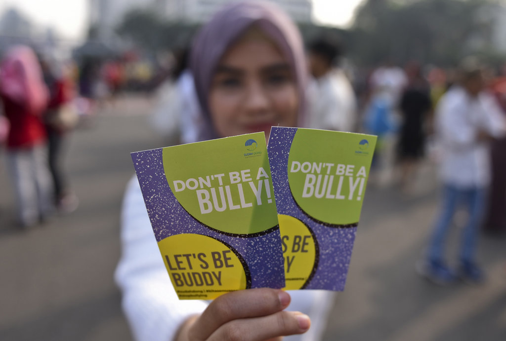 Seorang warga dari Komunitas Sudah Dong membentangkan stiker berisikan ajakan tidak melakukan 'bullying' saat hari bebas kendaraan bermotor di kawasan Bundaran HI, Jakarta, Minggu (23/7). ANTARA FOTO/Hafidz Mubarak A. AJAKAN STOP BULLYING