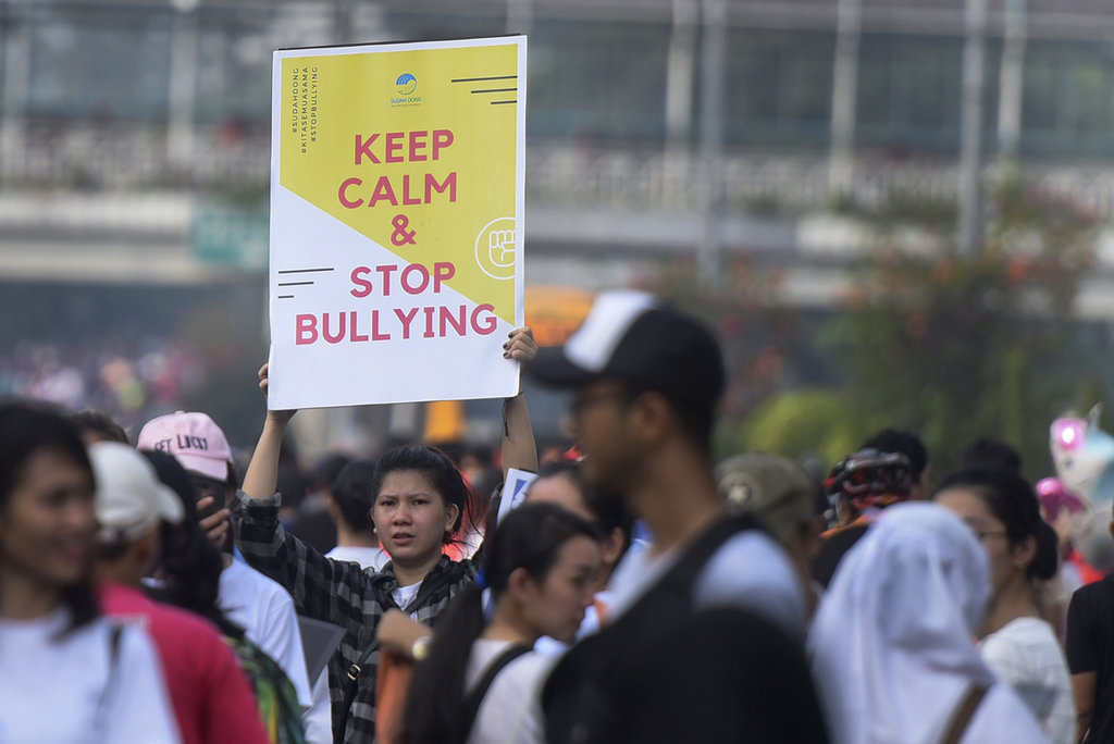 Seorang warga dari Komunitas Sudah Dong membentangkan poster berisikan ajakan tidak melakukan 'bullying' saat hari bebas kendaraan bermotor di kawasan Bundaran HI, Jakarta, Minggu (23/7). ANTARA FOTO/Hafidz Mubarak A. AJAKAN STOP BULLYING