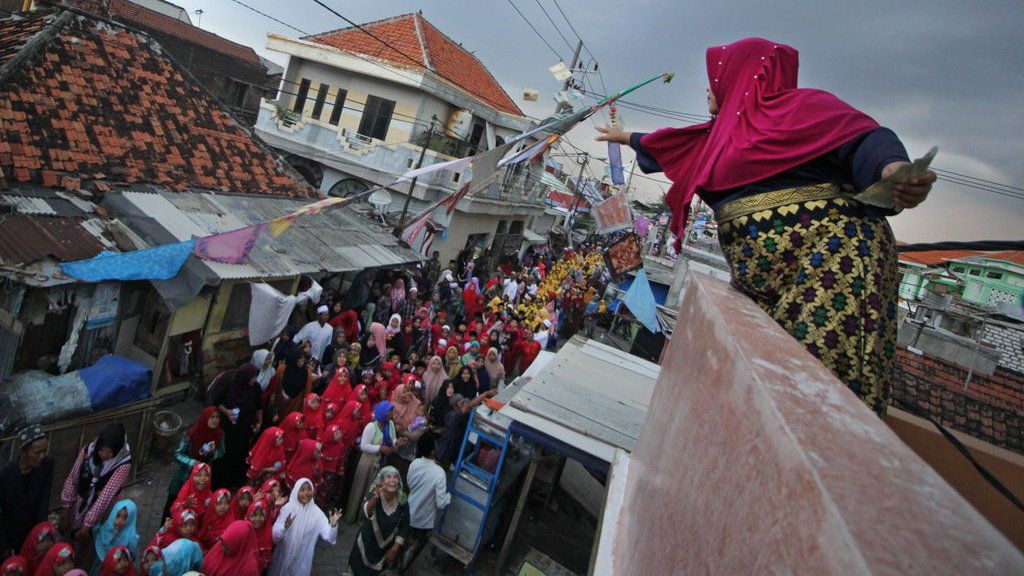 Seorang warga menebarkan uang kepada peserta pawai Maulid Nabi di Surabaya, Jawa Timur, Senin (19/11/2018). ANTARA FOTO/Moch Asim PAWAI MAULID NABI
