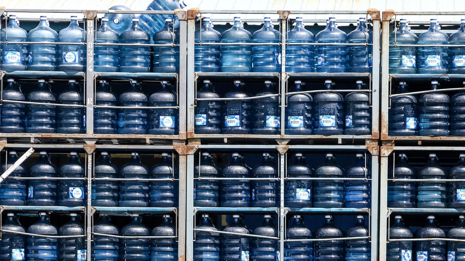 Pekerja melintas di depan depo pengisian air minum dalam kemasan Daan Mogot, Jakarta, Sabtu (7/8/2021). ANTARA FOTO/Rivan Awal Lingga/foc. OPTIMISTIS PPERTUMBUHAN INDUSTRI MAMIN