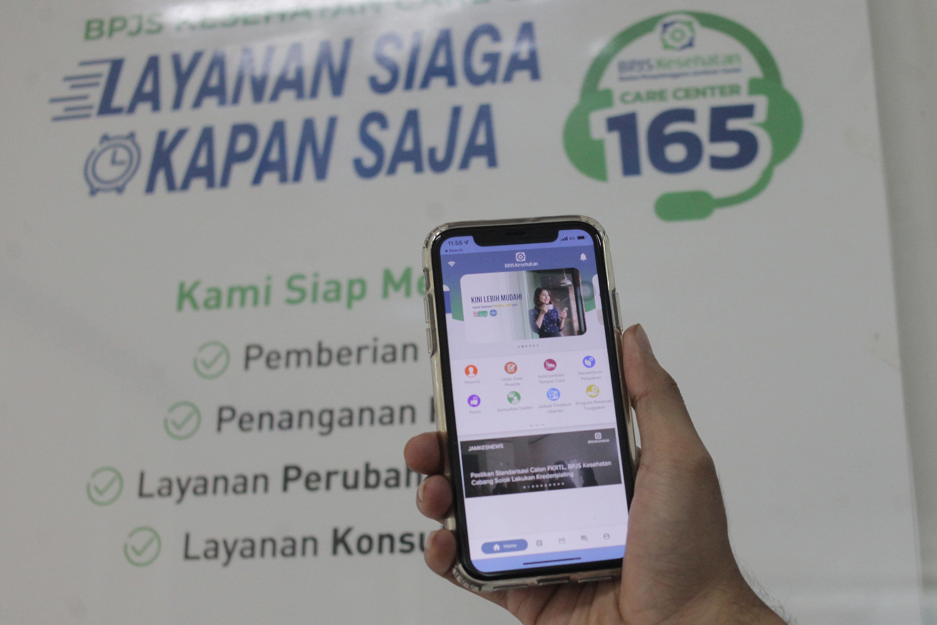 Warga menunjukkan fitur layanan BPJS Kesehatan. ANTARA FOTO/Reno Esnir/rwa. LAYANAN CARE CENTER BPJS KESEHATAN