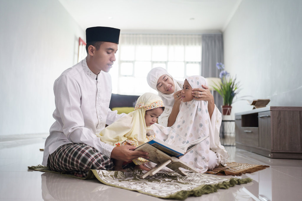 Ilustrasi - Keluarga muslim bersama anak-anak membaca Al-Quran setelah melakukan shalat bersama di rumah. (FOTO/iStockphoto) Shalat di Rumah