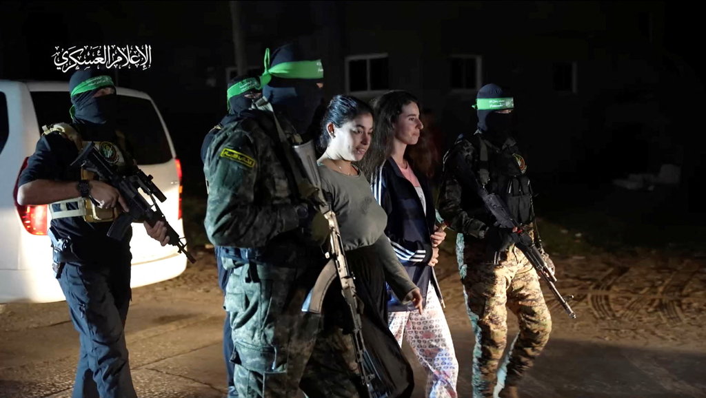 Para sandera yang diculik oleh orang-orang bersenjata Hamas selama serangan 7 Oktober terhadap Israel diserahkan oleh militan Hamas ke Palang Merah Internasional, sebagai bagian dari kesepakatan pertukaran sandera-tahanan antara Hamas dan Israel di tengah gencatan senjata sementara, di lokasi yang tidak diketahui di Israel. Jalur Gaza, (30 /11/2023). Sayap/Handout Militer Hamas via REUTERS Pembebasan Sandera Israel oleh Hamas