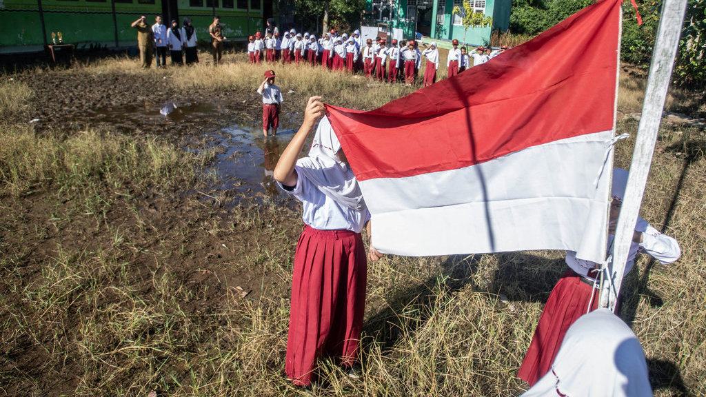 Upacara bendera di halaman yang tergenang air dan berlumpur