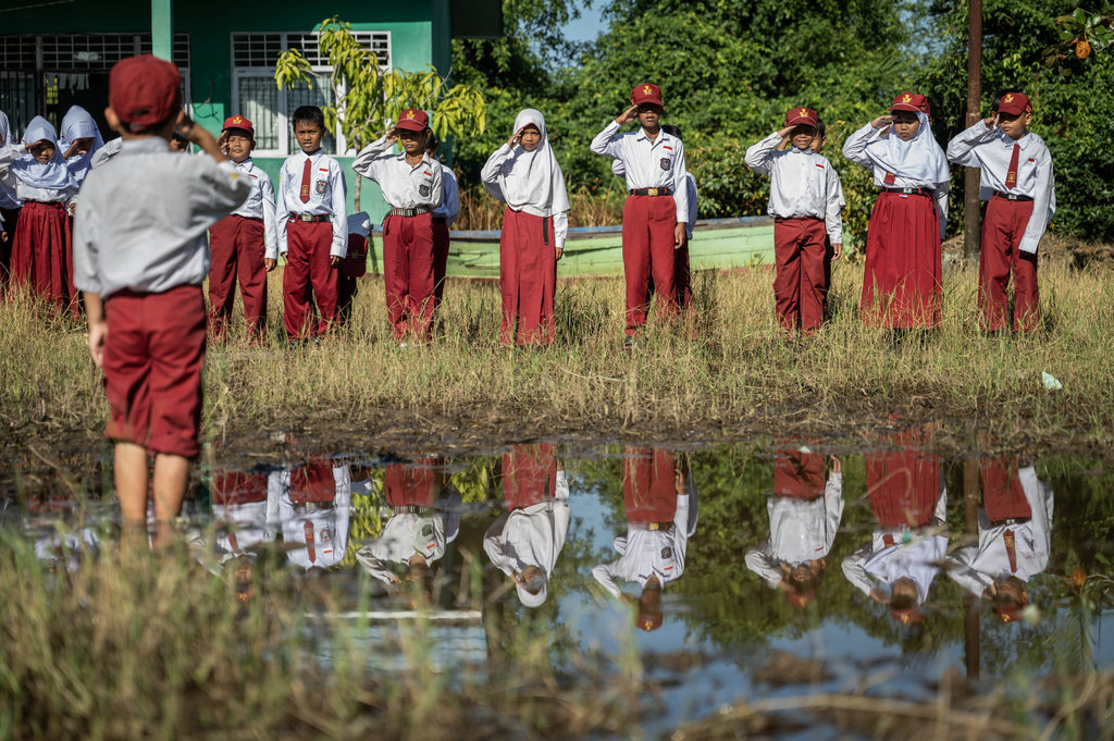 Upacara bendera di halaman yang tergenang air dan berlumpur
