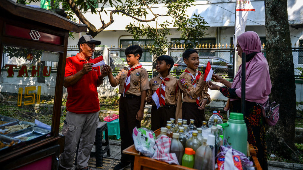 Siswa SDN Patrakomala memberikan bendera merah putih kepada pedagang di Jalan Menado, Bandung, Jawa Barat, Rabu (14/8/2024). ANTARA FOTO/Raisan Al Farisi/foc. Peringati Hari Pramuka di Bandung