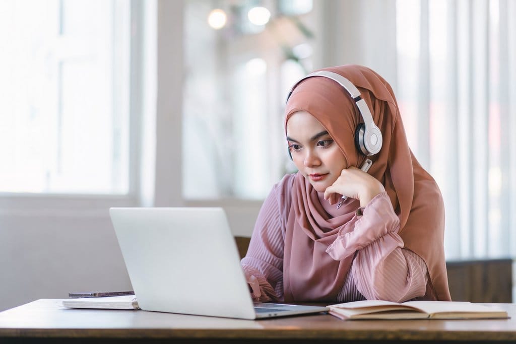 Perempuan berjilbab menghadap laptop