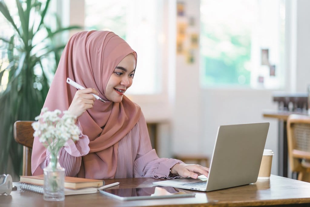 Mahasiswa menggunakan laptop. FOTO/iStockphoto Perempuan berjilbab menghadap laptop