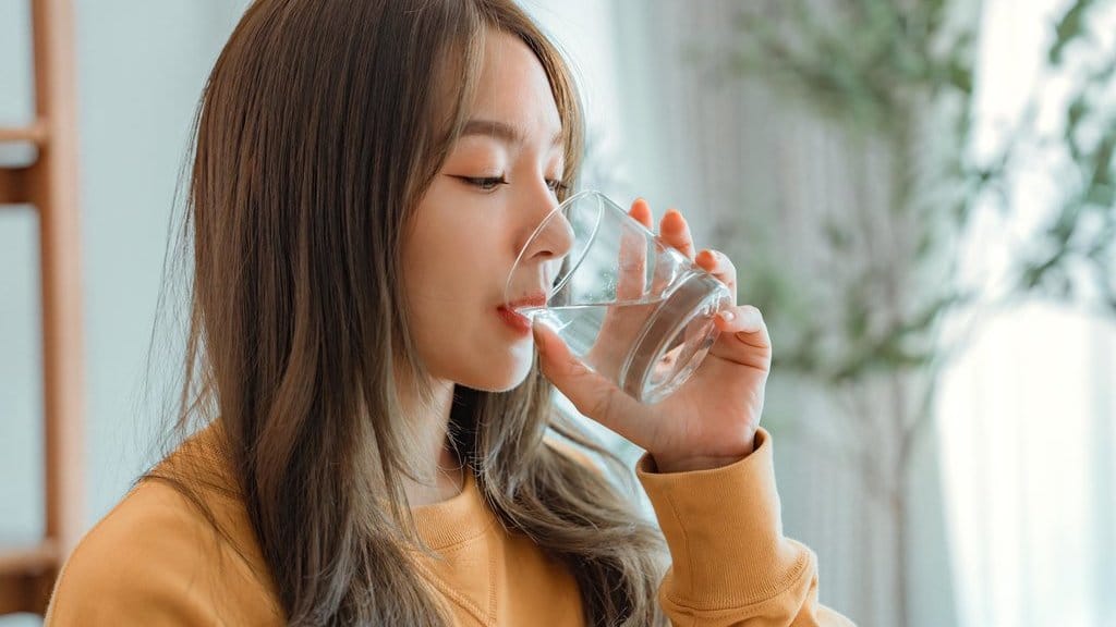 Ilustrasi Seorang Wanita Minum Air Putih. foto/istockphoto Ilustrasi Seorang Wanita Minum Air Putih