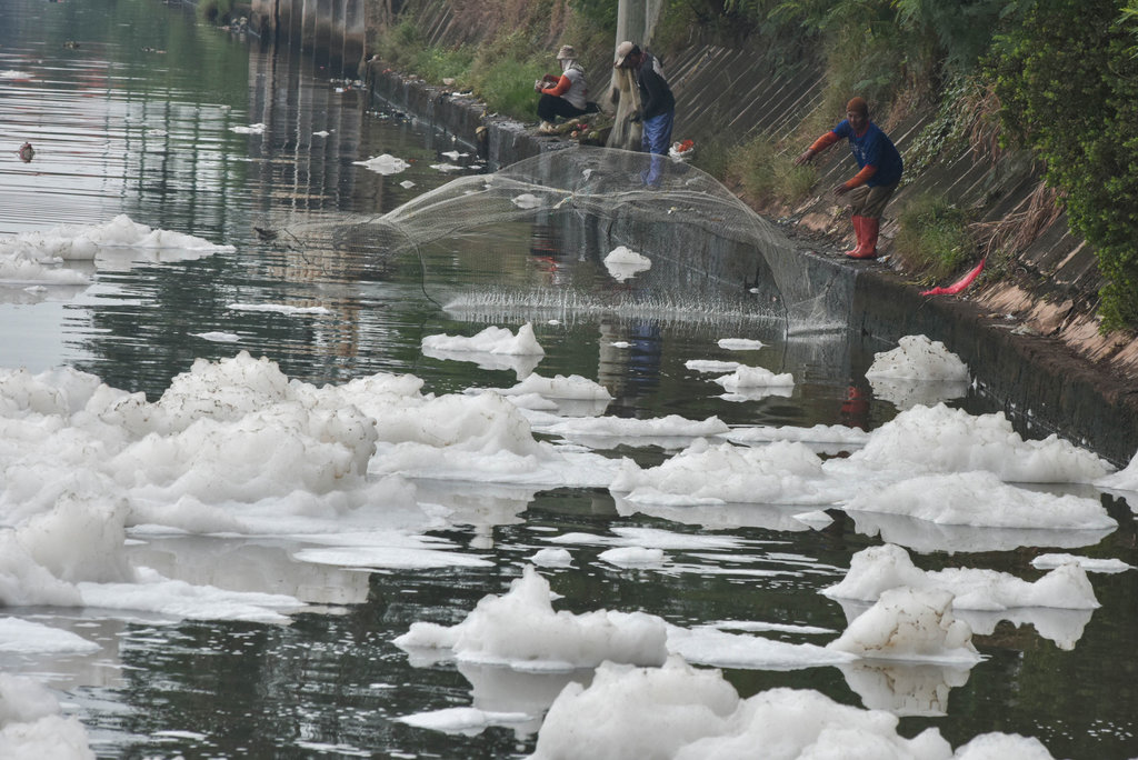 Warga menjala ikan di Pintu Air 3 Kanal Banjir Timur (KBT) yang tercampur limbah busa di Marunda, Jakarta Utara, Kamis (19/6/2025). ANTARA FOTO/Fakhri Hermansyah Air KBT tercampur limbah busa