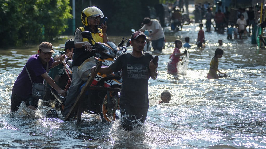 Warga menggunakan gerobak mengangkut sepeda motor dan pengendara melintasi banjir di Kembangan, Jakarta Barat, Selasa (8/7/2025). Banjir setinggi 60 cm akibat luapan Kali Angke tersebut membuat arus lalu lintas jalan yang menghubungkan Puri Kembangan ke Cengkareng terhambat dan sejumlah kendaraan roda dua mogok. ANTARA FOTO/Putra M. Akbar/agr Akses jalan terganggu akibat banjir di Jakarta