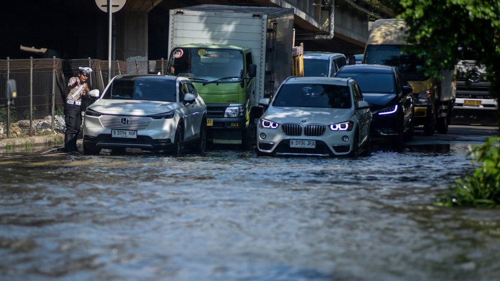 Polisi memberikan imbauan kepada pengendara mobil yang akan melintasi banjir di Kembangan, Jakarta Barat, Selasa (8/7/2025). Banjir setinggi 60 cm akibat luapan Kali Angke tersebut membuat arus lalu lintas jalan yang menghubungkan Puri Kembangan ke Cengkareng terhambat dan sejumlah kendaraan roda dua mogok. ANTARA FOTO/Putra M. Akbar/agr Akses jalan terganggu akibat banjir di Jakarta