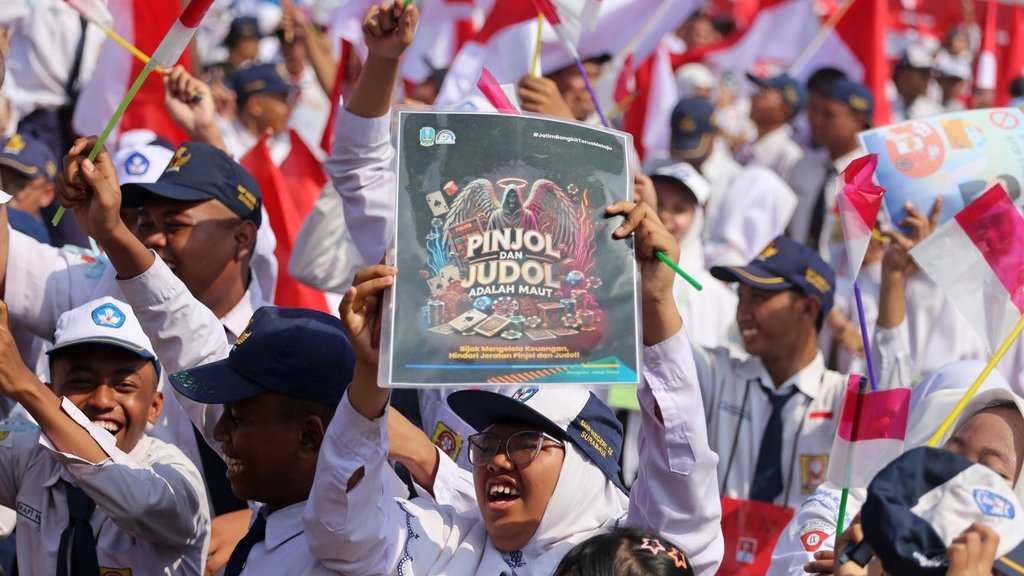 Pelajar membentangkan poster anti judi online (judol) dan Bendera Merah Putih saat pembukaan Masa Pengenalan Lingkungan Sekolah (MPLS) dengan tema Ramah untuk jenjang SMA, SMK dan SLB di halaman SMA Hang Tuah 1, Surabaya, Jawa Timur, Senin (14/7/2025). ANTARA FOTO/Moch Asim/YU Pembukaan MPLS di Jawa Timur