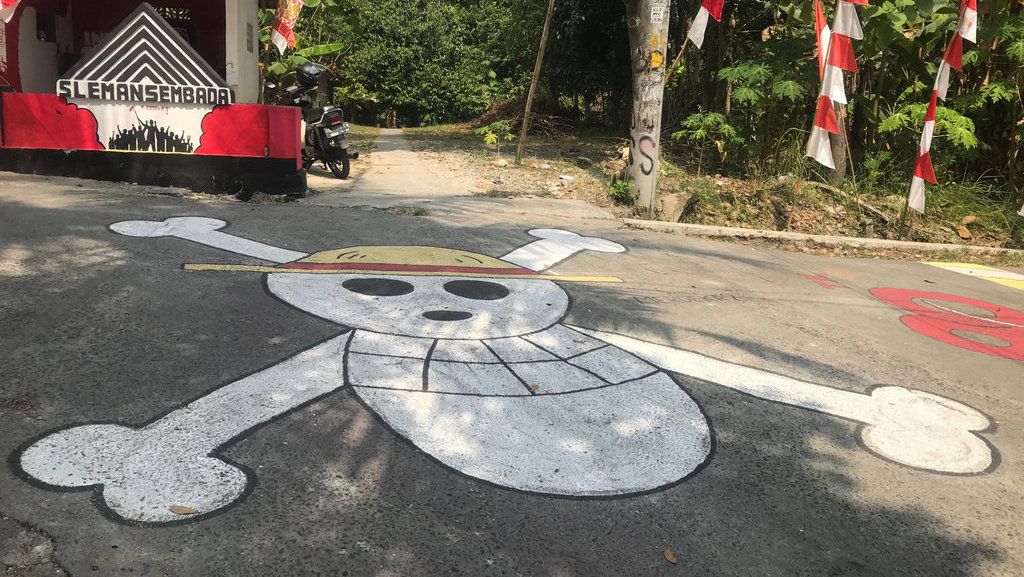 Sebuah lukisan mural One Piece di persimpangan Jalan di Pedukuhan Temuwuh, Balecatur, Gamping, Kabupaten Sleman. tirto.id/Abdul Haris. Mural One Piece di Sleman