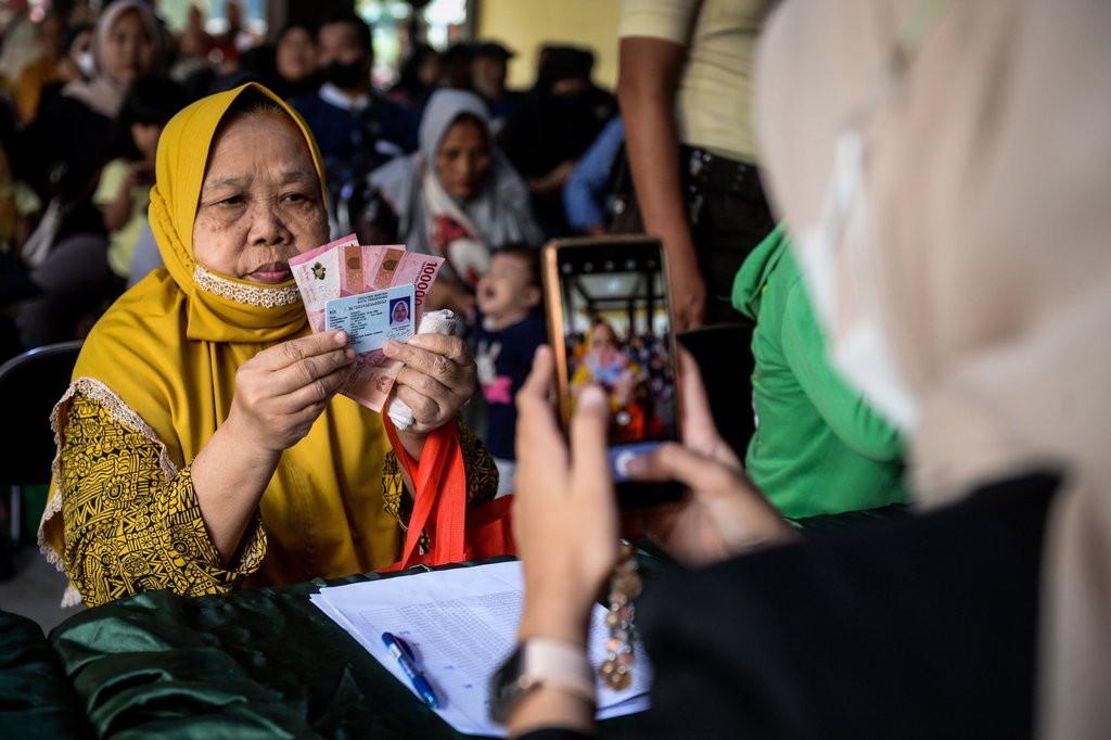 Petugas memotret warga memperlihatkan uang tunai saat penyaluran bantuan sosial di Kota Tangerang, Banten, Selasa (12/8/2025). ANTARA FOTO/Putra M. Akbar/foc. Realisasi penyaluran bantuan sosial di Banten