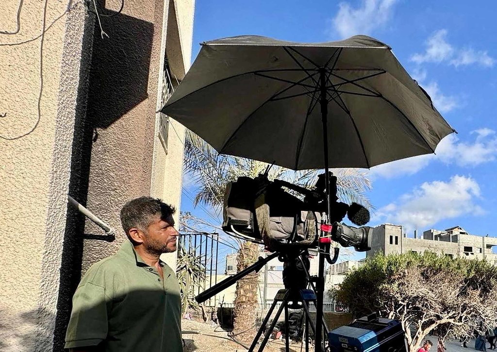 Jurnalis Reuters Hussam al-Masri, yang tewas akibat serangan Israel di Rumah Sakit Nasser pada 25 Agustus 2025, berdiri di samping kameranya saat bekerja di rumah sakit di Khan Younis dalam foto tanpa tanggal ini. REUTERS/Mohammed Salem/Foto File Hussam al Masri