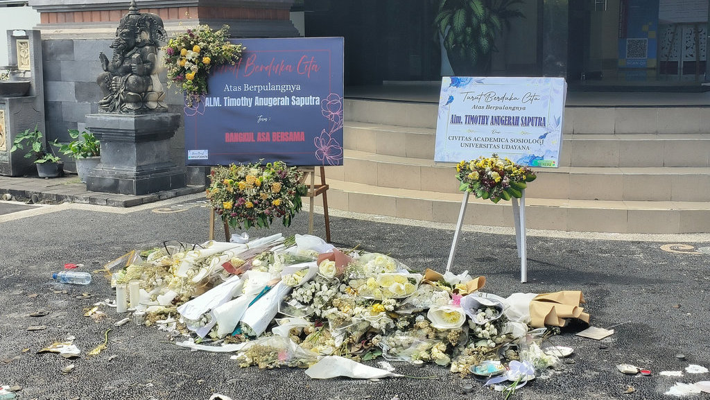 Karangan bunga di depan Gedung Fakultas Ilmu Sosial dan Ilmu Politik (FISIP) Universitas Udayana untuk mengenang Timothy Anugerah Saputra, Senin (20/10/2025). Tirto.id/Sandra Gisela Karangan bunga di FISIP Universitas Udayana