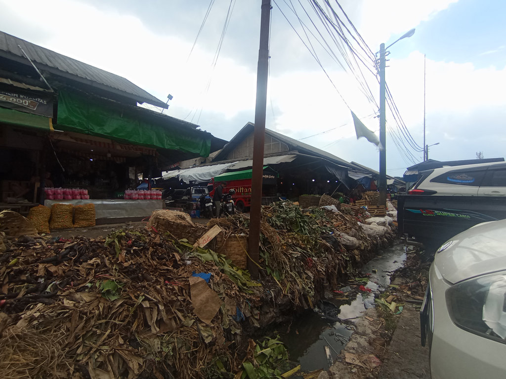 Kondisi tumpukan sampah di TPS Pasar Induk Caringin, Kota Bandung yang masih menggunung, pada pertengahan Oktober 2025 lalu. Sejumlah tumpukan sampah pun tampak di depan kios pedagang. tirto.id/Amad NZ TPS Pasar Induk Caringin