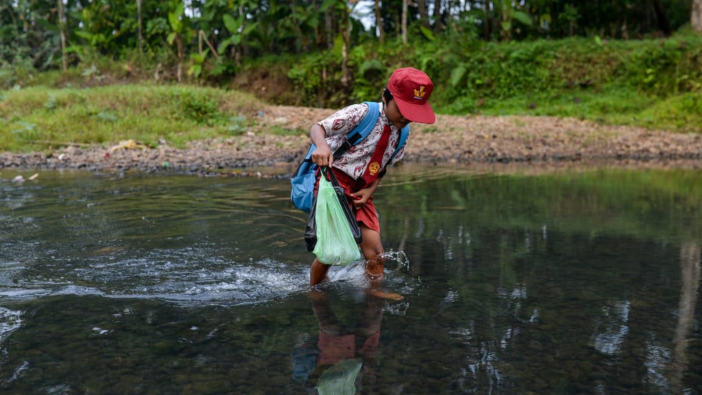 Siswa SD Negeri Padahayu 2 berjalan menyeberangi Sungai Cipunten Agung di Cikedal