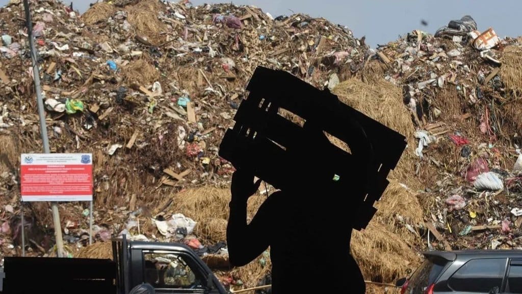 Buruh angkut berjalan di dekat tumpukan sampah yang meluber di TPS Pasar Induk Kramat Jati