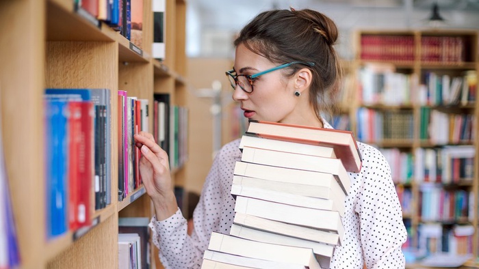 Seorang wanita sedang memilih buku di perpustakaan. Foto/iStockphoto