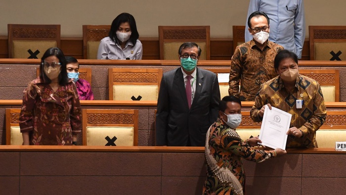 Menko Perekonomian Airlangga Hartarto (kanan) didampingi Menkumham Yasonna Laoly (kedua kiri) dan Menteri Keuangan Sri Mulyani (kiri) menerima laporan akhir dari Ketua Badan Legislasi DPR Supratman Andi (bawah) saat pembahasan tingkat II RUU Cipta Kerja pada Rapat Paripurna DPR di Kompleks Parlemen, Jakarta, Senin (5/10/2020). ANTARA FOTO/Hafidz Mubarak A.