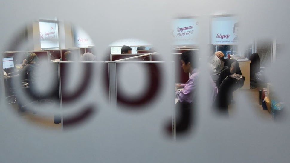  The image shows a group of people working in cubicles with a frosted glass door with the words 'layanan 1500 655' and 'Sigap' etched into the glass.